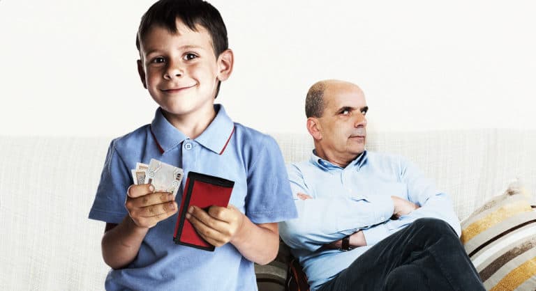 صورة طفل يغيظ والده بعدِّ نقود العيديَّة التي أخذها منه