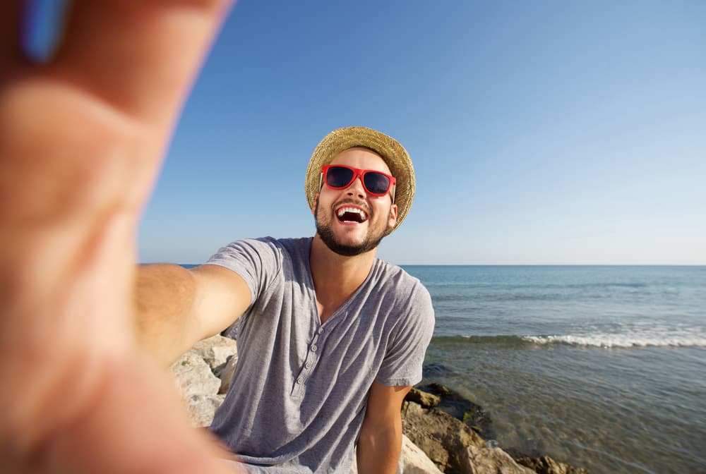 صورة شاب يأخذ مجموعة كبيرة من الصور خلال إجازته كأدلة لإثبات أنه سعيد