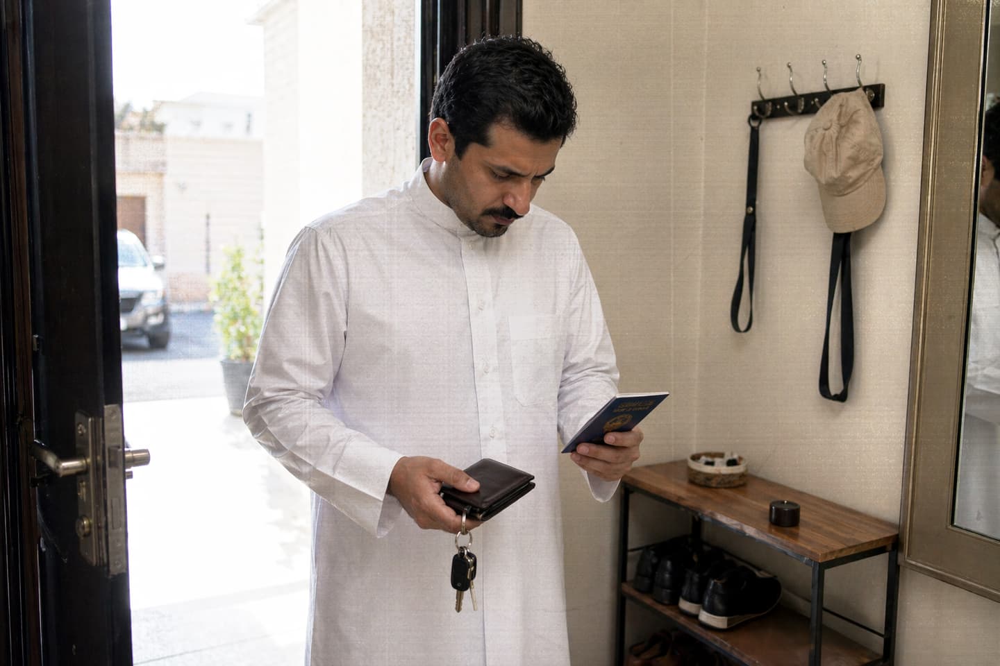 صورة كويتي يتفقد بطاقة الصرّاف ومفتاح شقته وجنسيته قبل مغادرة المنزل