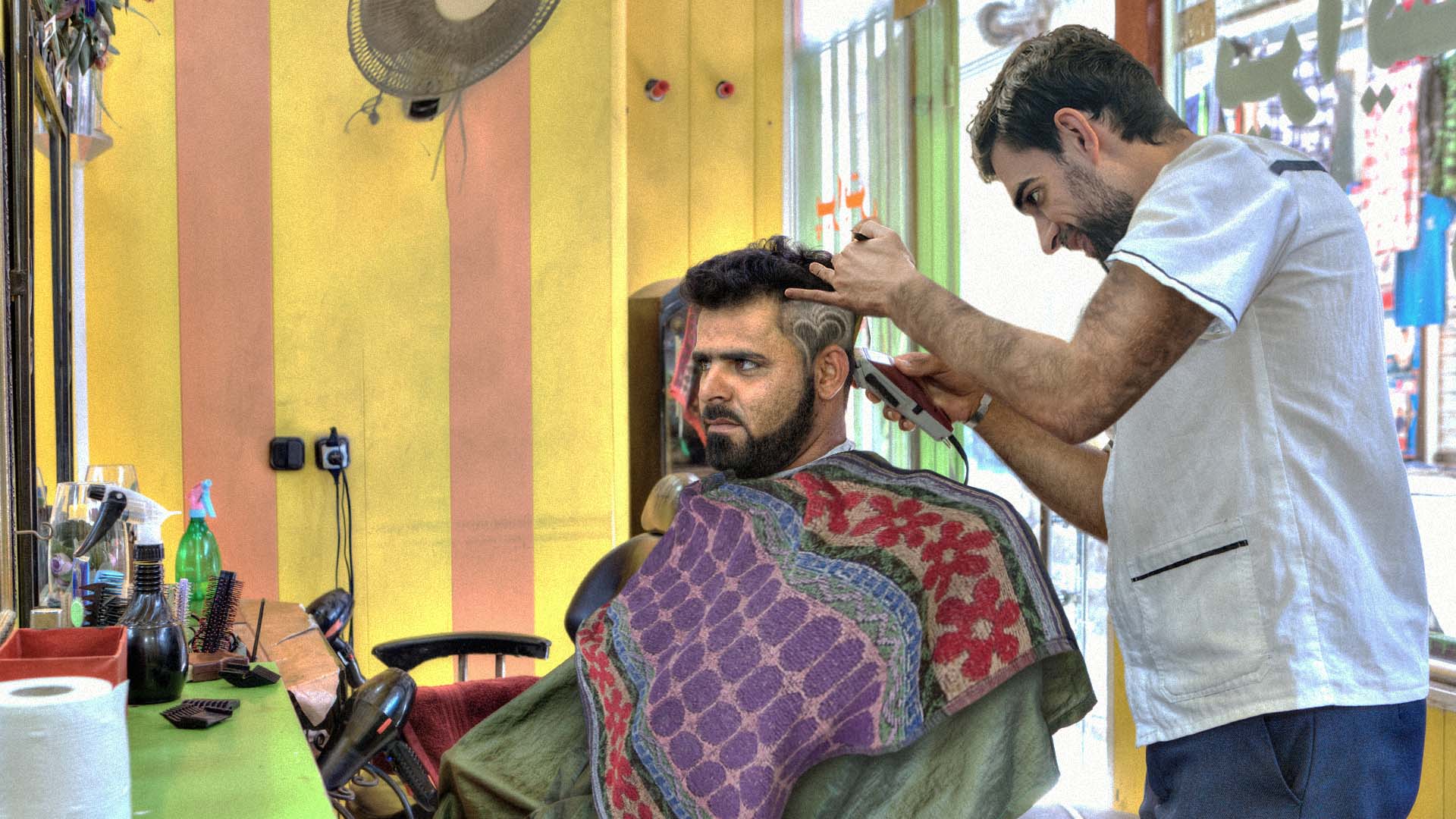 صورة حلّاق ينصت لطلب زبونه بحذر واهتمام ليتسنى له مخالفته بأدق شكل ممكن